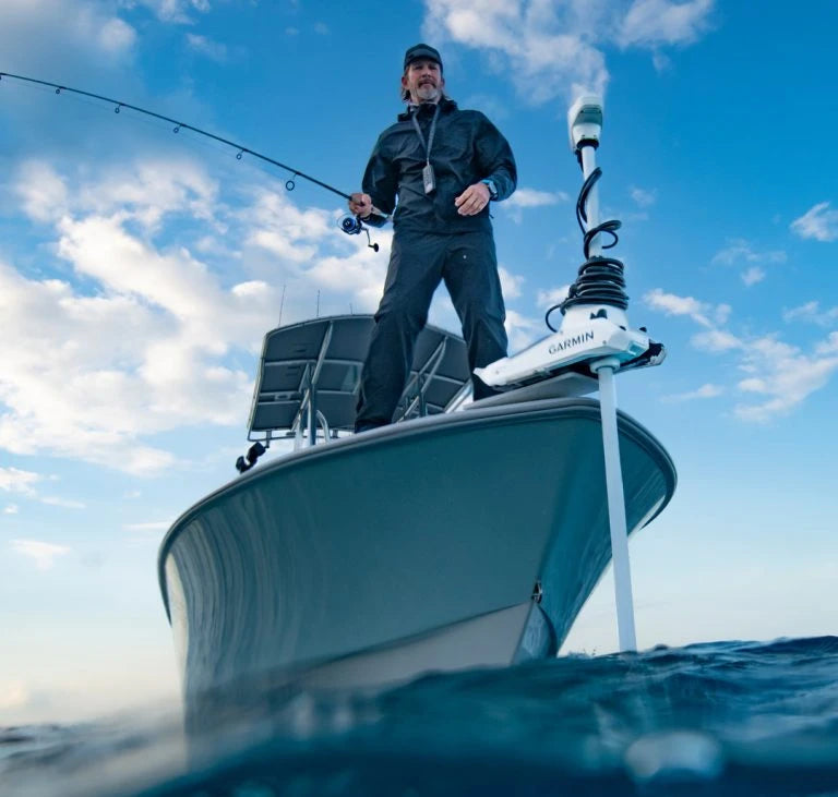 Man standng at the bow of white boat using a fishing rod next to the Garmin Force Kraken Trolling Motor