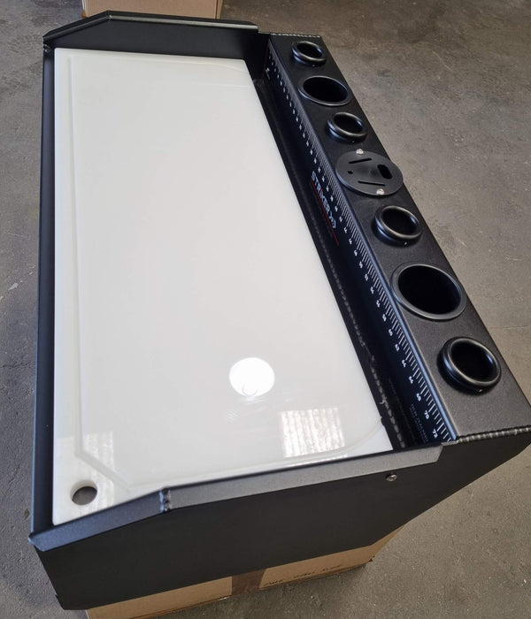 A top-down view of a marine bait board showing the cutting board, storage compartment, and multiple rod holders. The board is made from durable aluminum and is perfect for organizing fishing gear and preparing bait on the water.