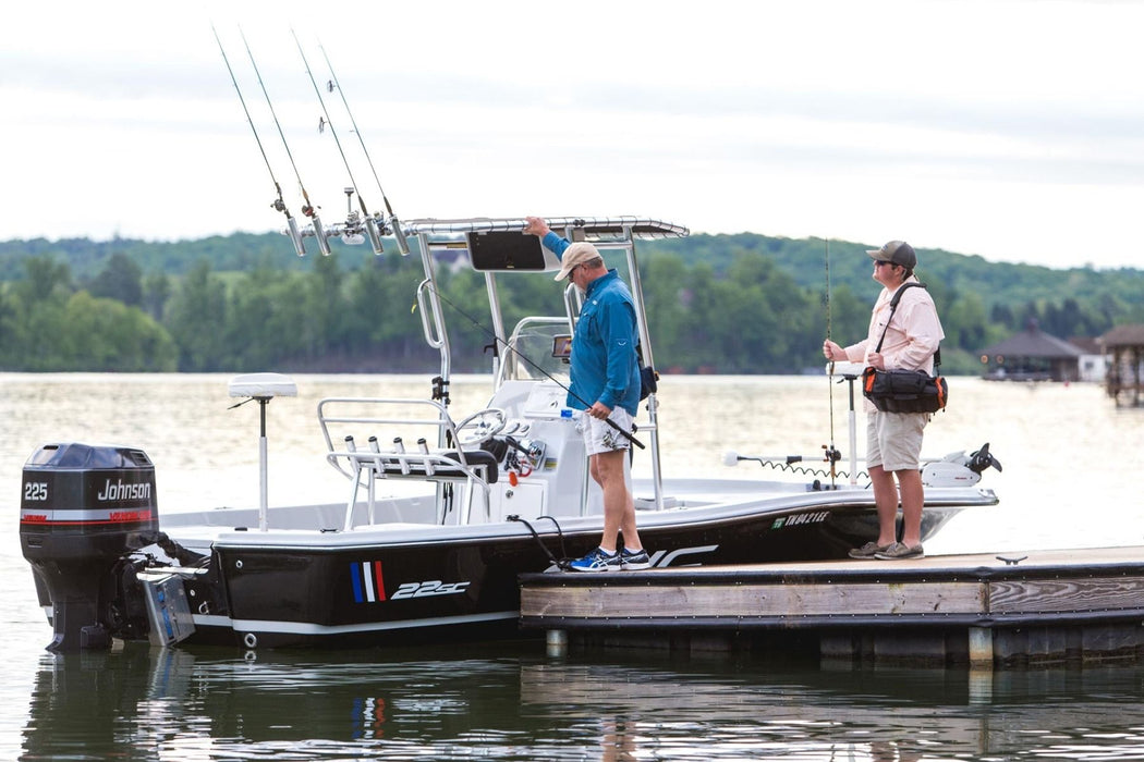 A Fishmaster T-top mounted on an Epic 22C boat, powered by a Johnson outboard engine. The boat is docked at a marina with a scenic background.