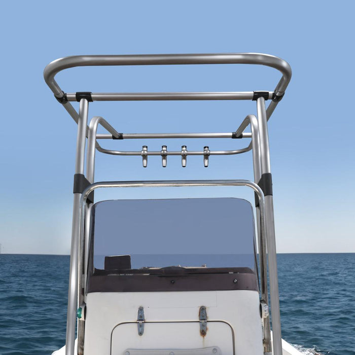 A close-up view of a boat T-top with multiple rod holders mounted on the top. The T-top has a stainless steel frame and provides a platform for fishing rods. The boat is docked at a marina with a clear blue sky and calm water in the background.