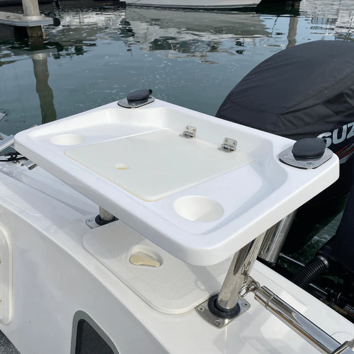 A white, rectangular fishing bait station mounted on the back of a boat with two outboard motors covered in black engine covers. The station has a hinged lid and several smaller compartments. The "SUZUKI" logo is visible on one of the engine covers.