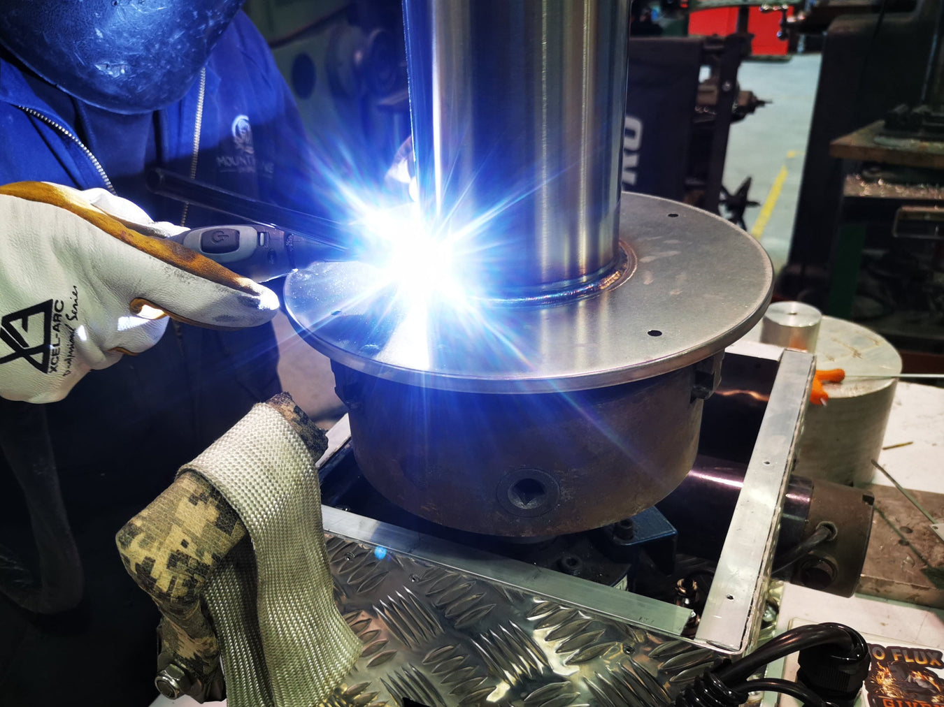 welder welding stainless steel pipe on a rotary machine